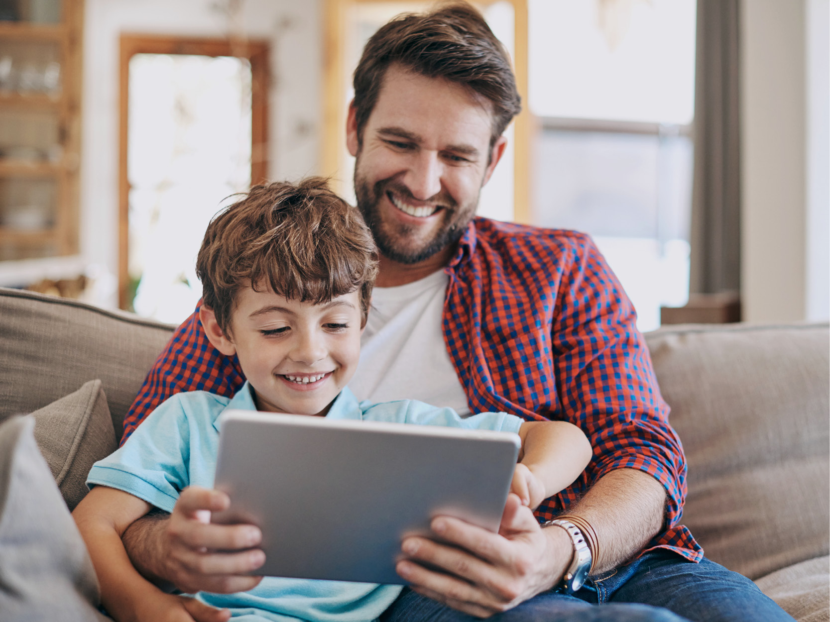 A father and son using fiber internet to surf the web on a tablet.